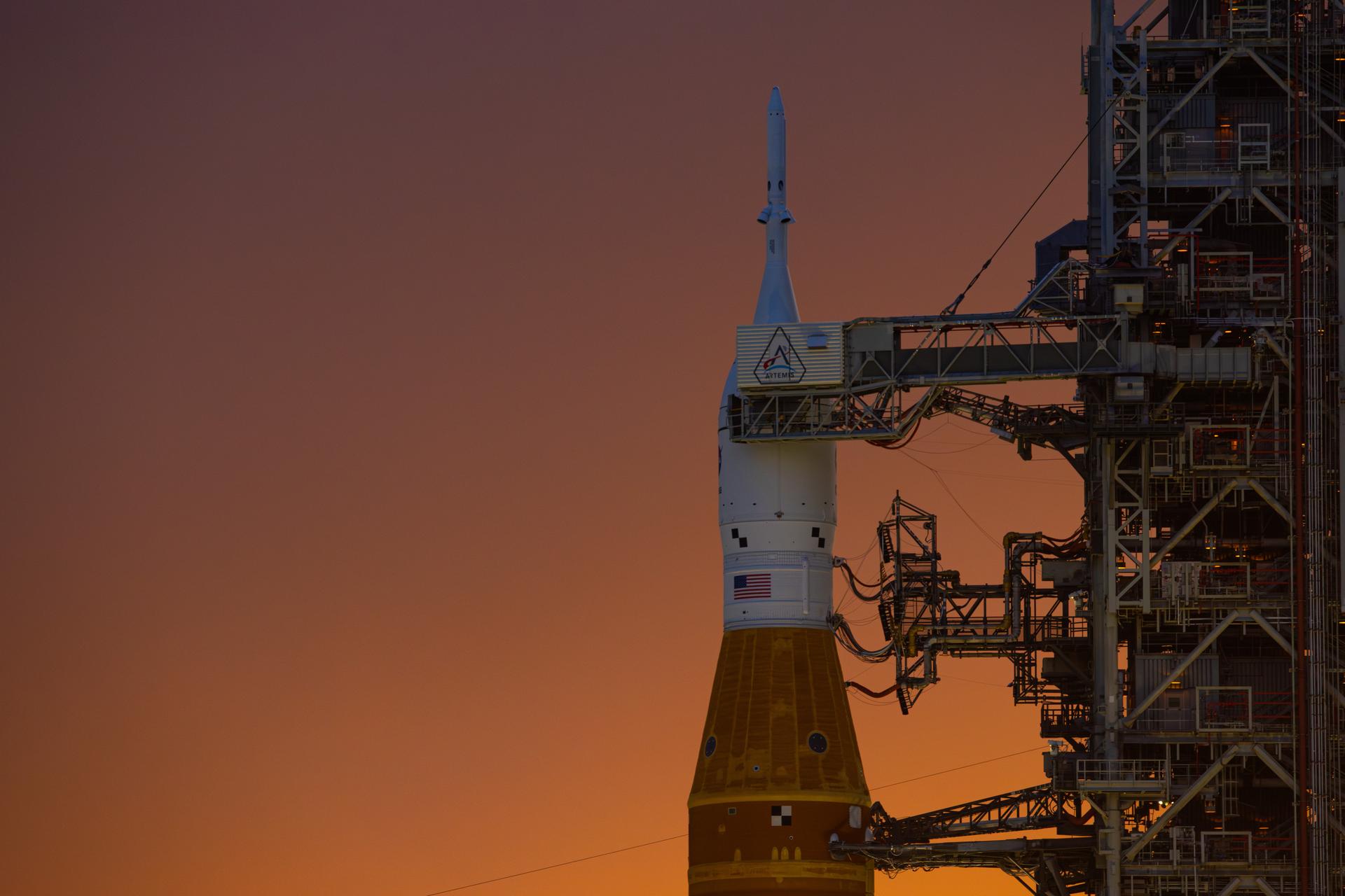 This image shows a sunset of NASA’s SLS (Space Launch System) and Orion spacecraft at NASA’s Kennedy Space Center. NASA's massive Crawler-Transporter, upgraded for the Artemis program, carried the powerful SLS rocket and Orion spacecraft on the Mobile Launcher from the Vehicle Assembly Building to Launch Pad 39B at Kennedy Space Center in preparation for the Artemis II mission.